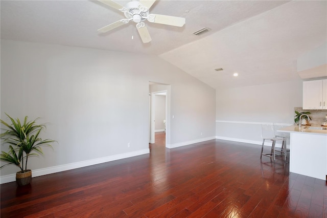 unfurnished living room featuring ceiling fan, dark hardwood / wood-style flooring, and vaulted ceiling