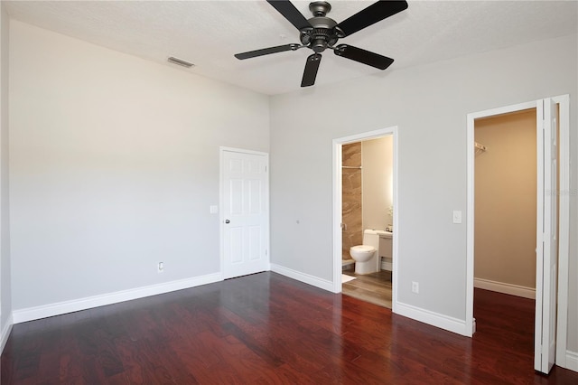 unfurnished bedroom featuring ensuite bathroom, ceiling fan, a spacious closet, dark hardwood / wood-style flooring, and a closet