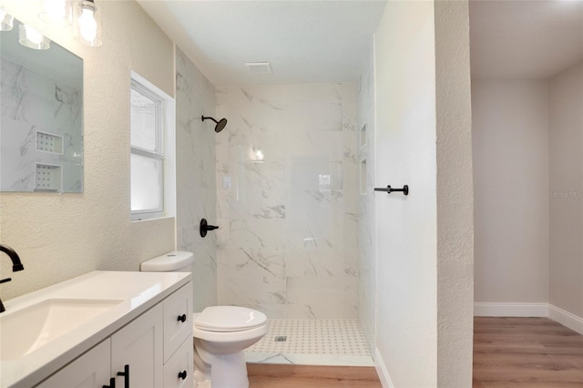 bathroom with vanity, a tile shower, and wood-type flooring