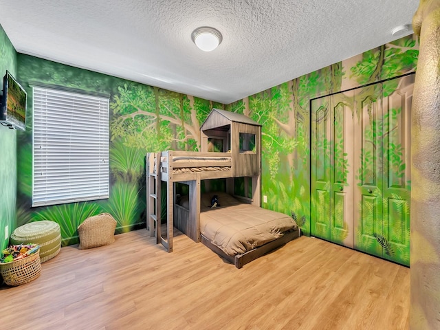 bedroom with a closet, hardwood / wood-style floors, and a textured ceiling