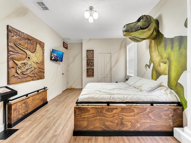 bedroom featuring a closet, light wood-type flooring, and a textured ceiling