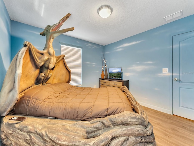 bedroom featuring light hardwood / wood-style floors and a textured ceiling