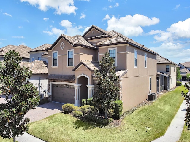 view of front of home with a front lawn, central AC unit, and a garage