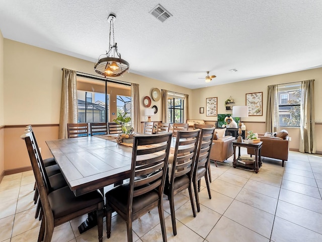 tiled dining room with a textured ceiling, plenty of natural light, and ceiling fan