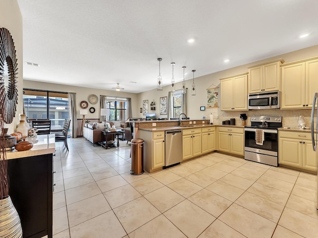 kitchen featuring kitchen peninsula, appliances with stainless steel finishes, decorative light fixtures, and light tile patterned floors