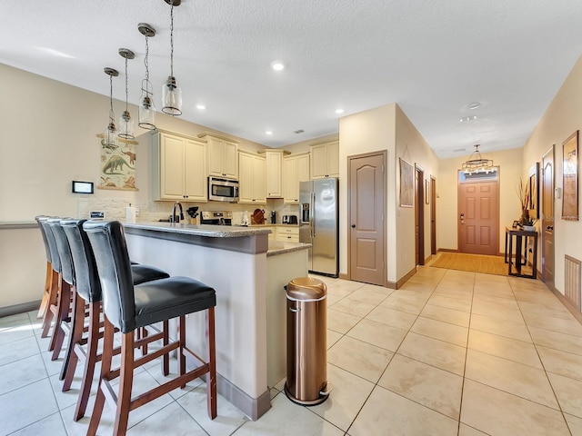 kitchen with kitchen peninsula, appliances with stainless steel finishes, hanging light fixtures, and a breakfast bar area