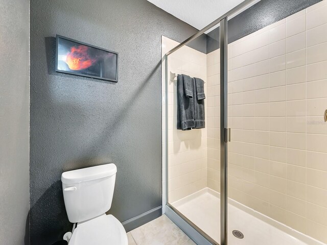 bathroom with toilet, a shower with shower door, and tile patterned floors