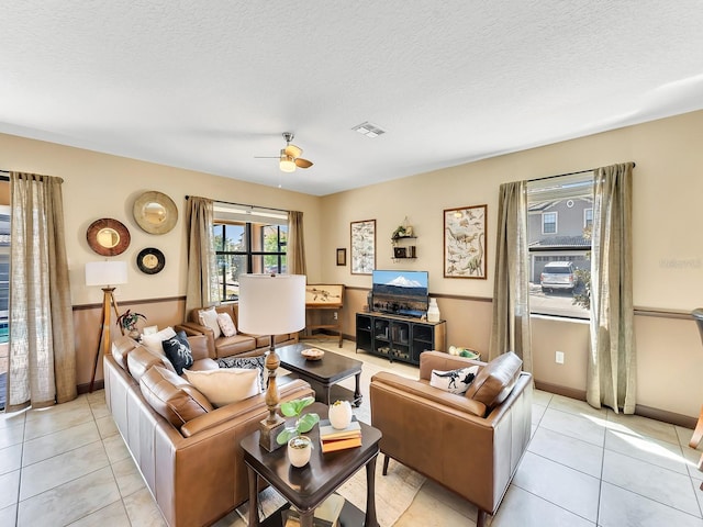 tiled living room with ceiling fan and a textured ceiling