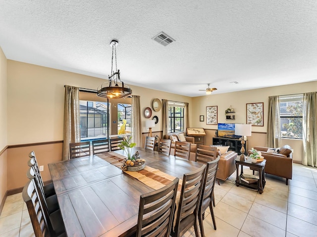 tiled dining room featuring a textured ceiling and ceiling fan