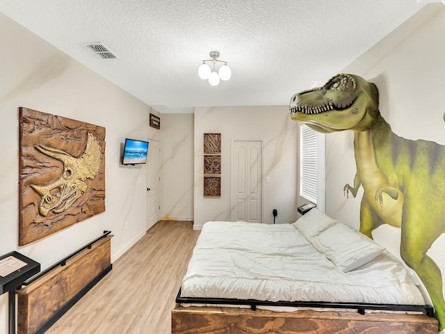 bedroom featuring light hardwood / wood-style flooring and a textured ceiling