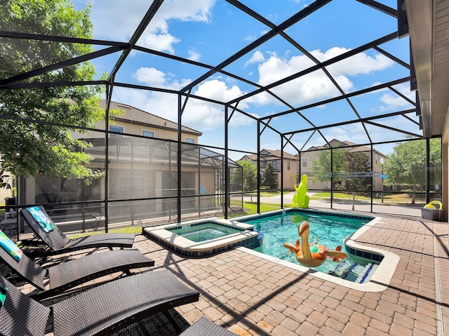 view of pool featuring an in ground hot tub, glass enclosure, and a patio area