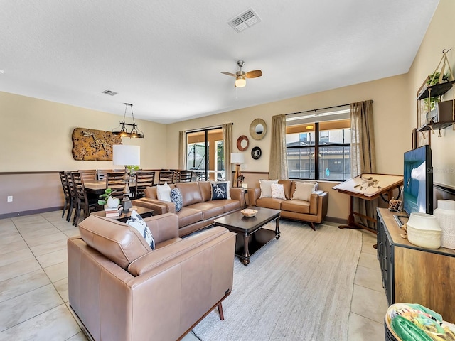 living room with ceiling fan, light tile patterned floors, and a textured ceiling