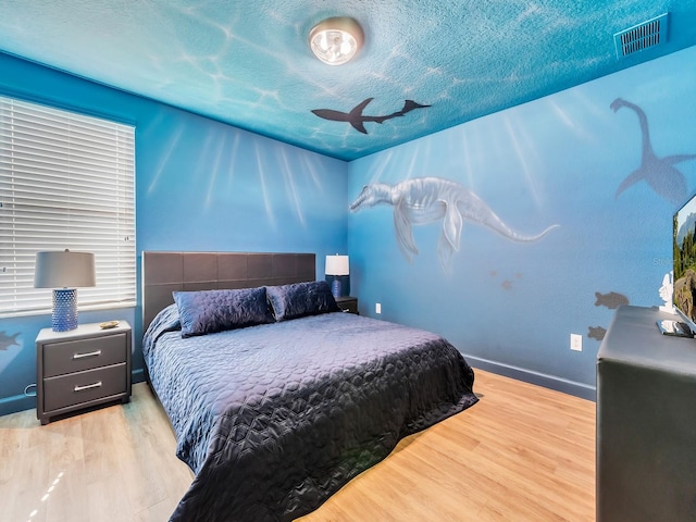 bedroom with a textured ceiling and light wood-type flooring