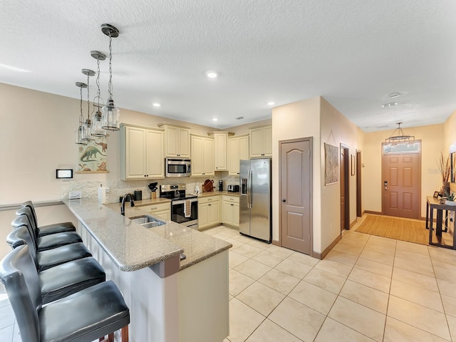 kitchen with kitchen peninsula, pendant lighting, stainless steel appliances, and sink