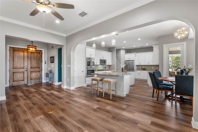 kitchen featuring tasteful backsplash, a center island with sink, white cabinetry, wood-type flooring, and stainless steel appliances