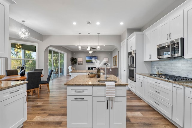 kitchen with appliances with stainless steel finishes, white cabinets, a kitchen island with sink, and sink