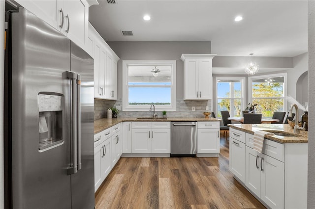 kitchen with decorative backsplash, white cabinets, appliances with stainless steel finishes, dark hardwood / wood-style floors, and sink