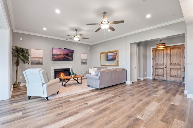 living room with light hardwood / wood-style floors, ornamental molding, and ceiling fan