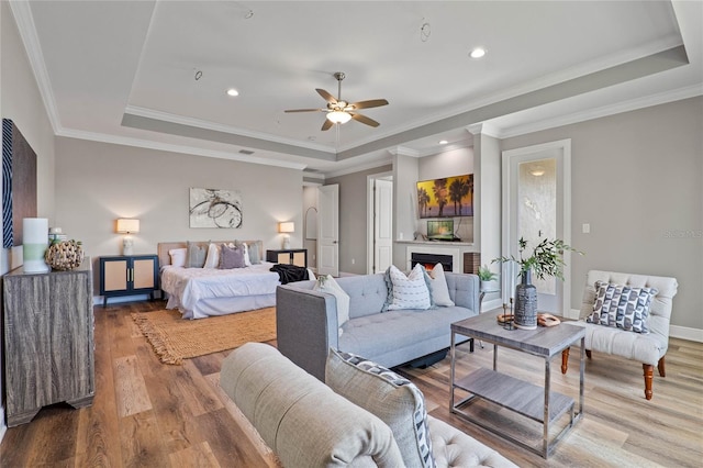 bedroom featuring crown molding, a raised ceiling, hardwood / wood-style flooring, and ceiling fan