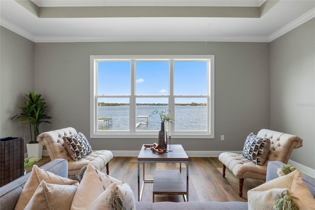 living area with crown molding, hardwood / wood-style flooring, and a water view