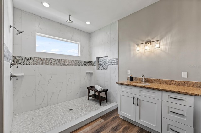 bathroom featuring a tile shower, vanity, and wood-type flooring