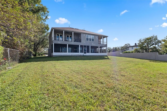 back of property with a yard and a balcony