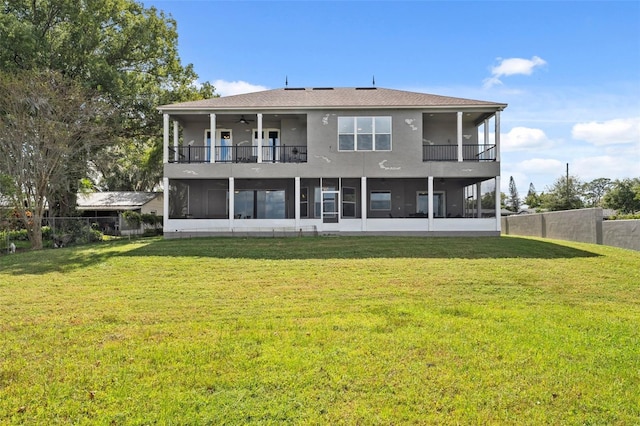 rear view of house featuring a yard, a sunroom, and a balcony