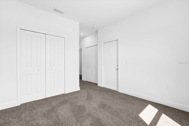 unfurnished bedroom with two closets and dark colored carpet