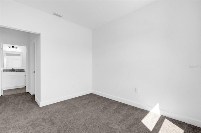 spare room featuring sink and dark carpet