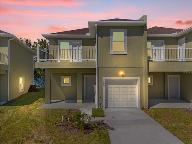 exterior space featuring a balcony, a yard, and a garage