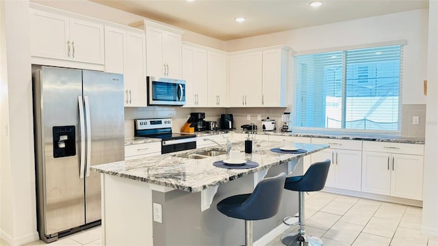 kitchen with appliances with stainless steel finishes, sink, white cabinets, decorative backsplash, and light tile patterned floors