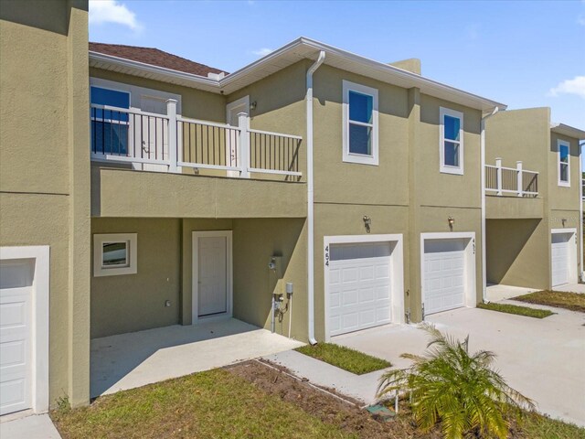454 Lake Shore Pkwy, Davenport, FL 33896 - back of property featuring a balcony, stucco siding, concrete driveway, and a garage