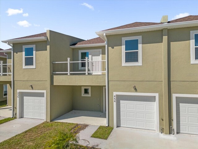 454 Lake Shore Pkwy, Davenport, FL 33896 - view of front of house featuring a garage, driveway, a balcony, and stucco siding