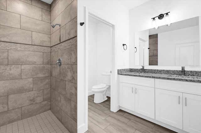 454 Lake Shore Pkwy, Davenport, FL 33896 - bathroom with tiled shower, double vanity, toilet, and wood finished floors