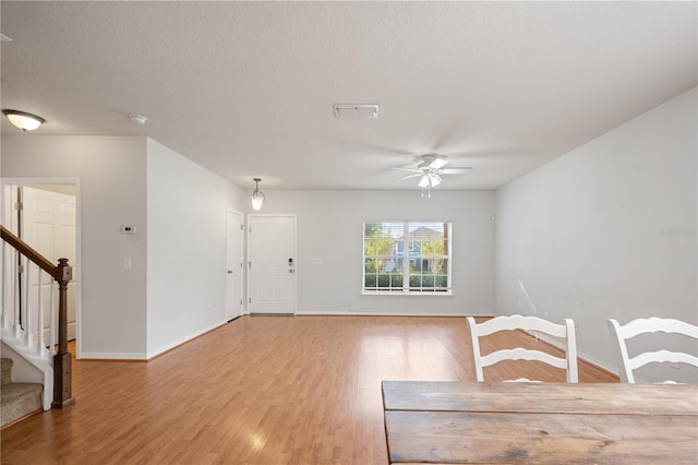 interior space with stairs, baseboards, light wood finished floors, and a textured ceiling