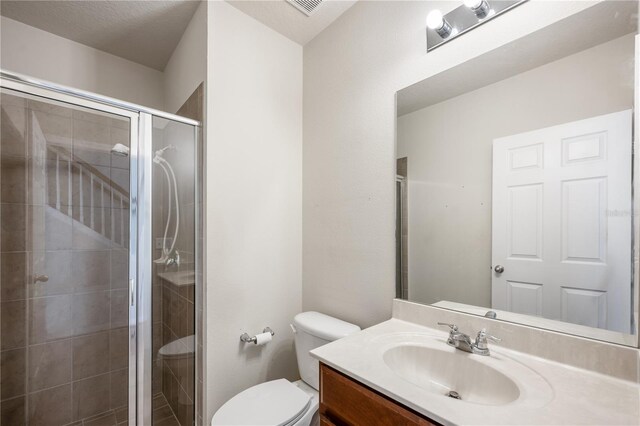 full bathroom with toilet, a stall shower, and vanity