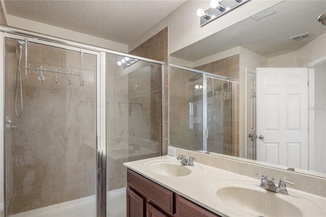 bathroom with visible vents, a shower stall, a textured ceiling, and a sink