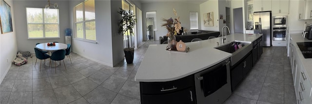 kitchen featuring hanging light fixtures, a center island with sink, white cabinetry, sink, and stainless steel appliances