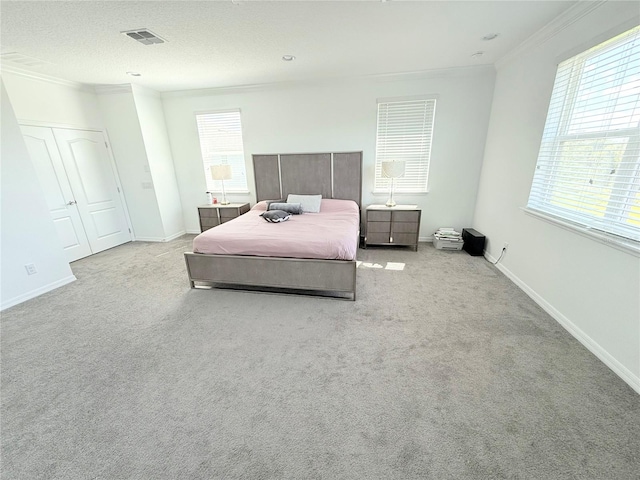 bedroom with crown molding, light carpet, and a textured ceiling