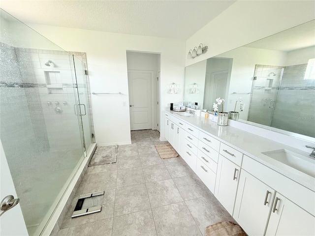 bathroom with a shower with door, vanity, a textured ceiling, and tile patterned flooring