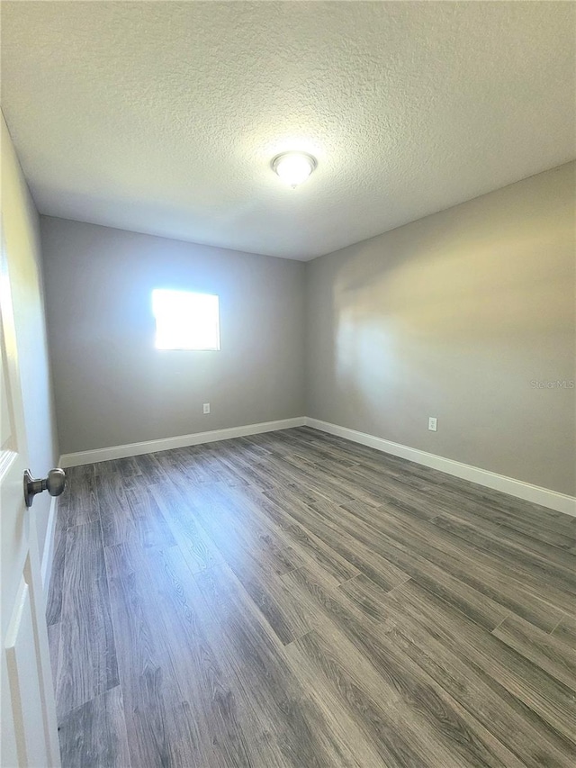 empty room featuring dark hardwood / wood-style flooring and a textured ceiling