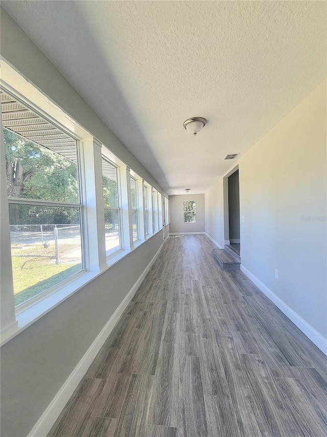 hallway with a textured ceiling and dark wood-type flooring