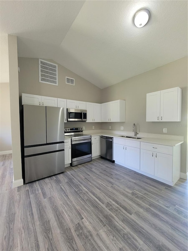 kitchen with stainless steel appliances, white cabinetry, light hardwood / wood-style floors, and sink