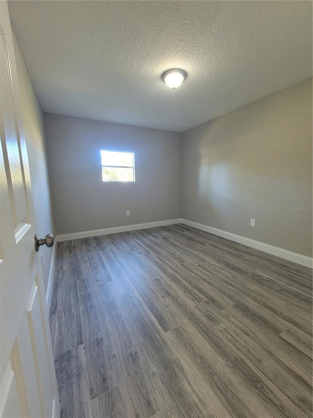 unfurnished room with dark hardwood / wood-style flooring and a textured ceiling