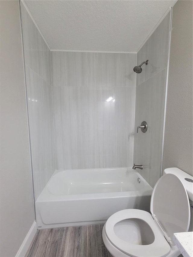 bathroom with hardwood / wood-style floors, tiled shower / bath, a textured ceiling, and toilet