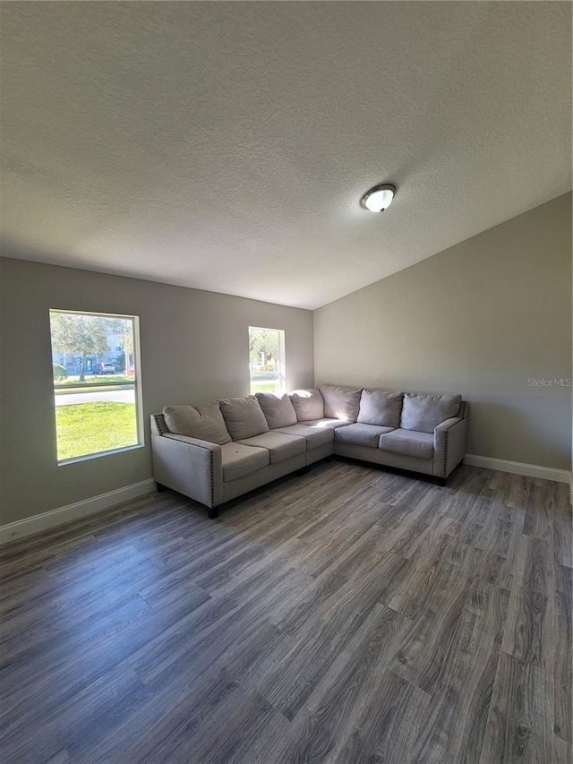 unfurnished living room with dark hardwood / wood-style flooring and a textured ceiling