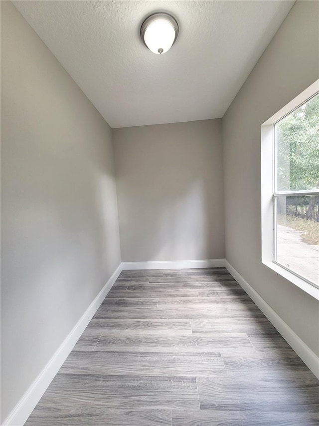 unfurnished room with a textured ceiling and light wood-type flooring