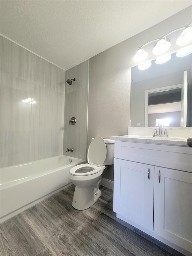 full bathroom featuring tiled shower / bath combo, hardwood / wood-style floors, a textured ceiling, toilet, and vanity