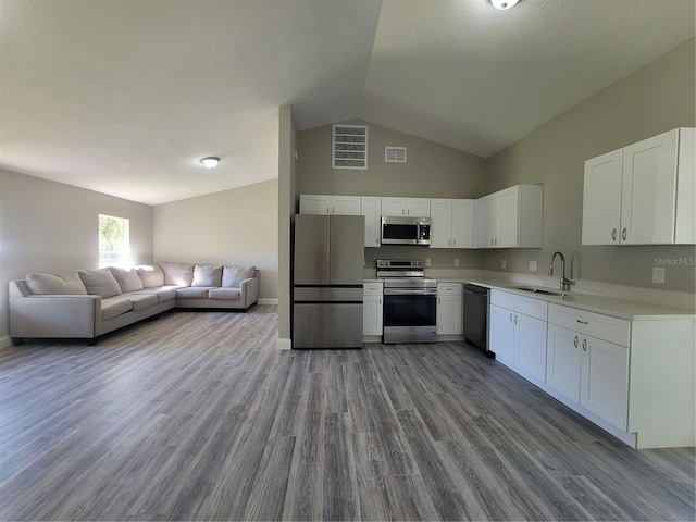 kitchen featuring appliances with stainless steel finishes, sink, light hardwood / wood-style flooring, white cabinets, and lofted ceiling