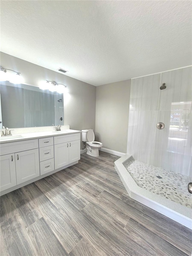 bathroom featuring wood-type flooring, vanity, a textured ceiling, and a tile shower